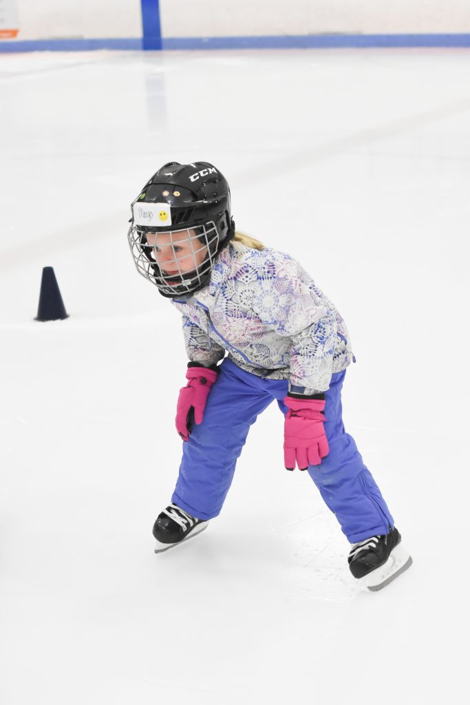 Child Learning to Skate in Hockey Helmet and Hockey Skates
