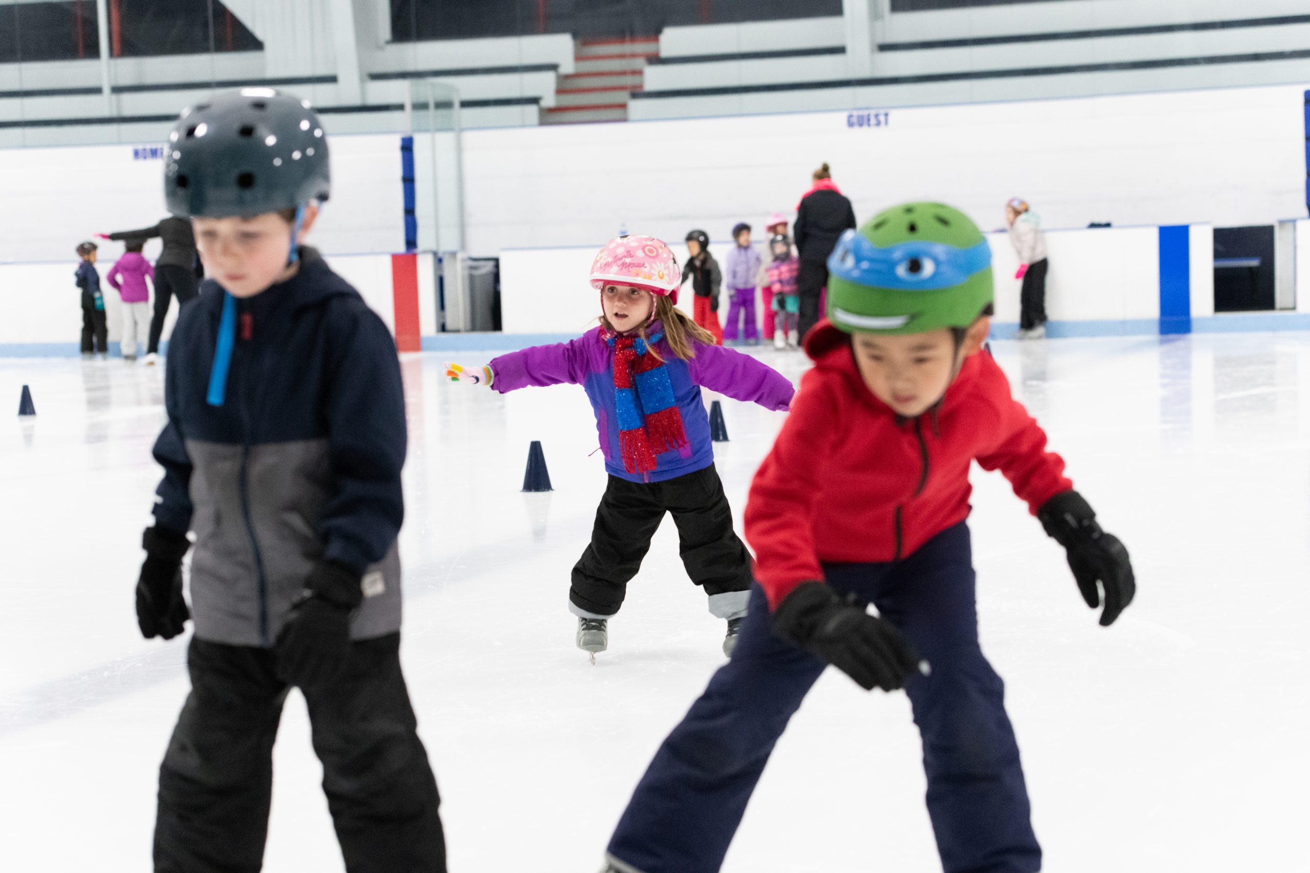 Three young children learning to skate
