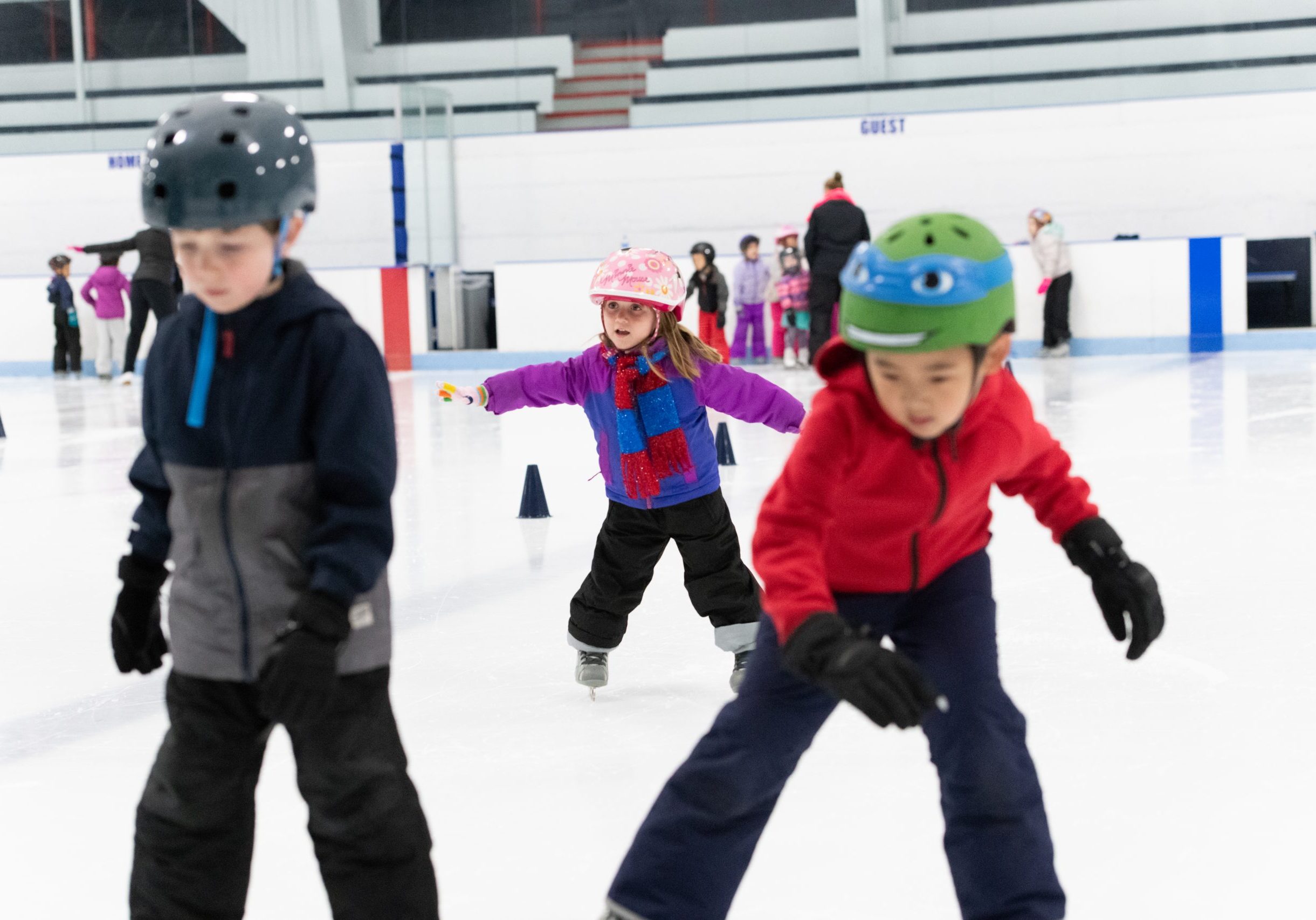 Three young children learning to skate