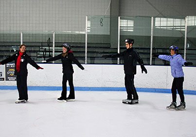 3 adults with instructor learning basic skating